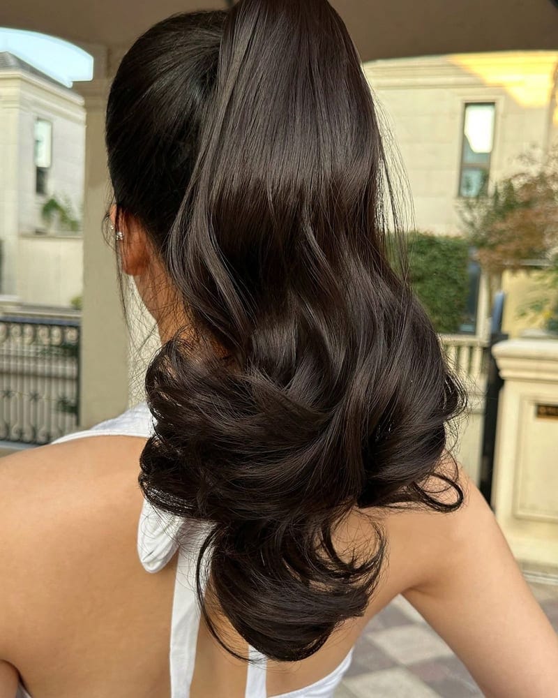 A wrap-around ponytail piece secured and styled into full, soft waves