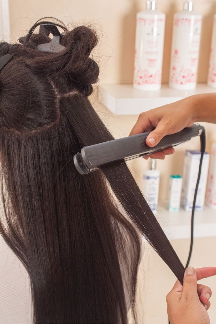 Smooth, glossy hair being finished with a flat iron after a keratin treatment