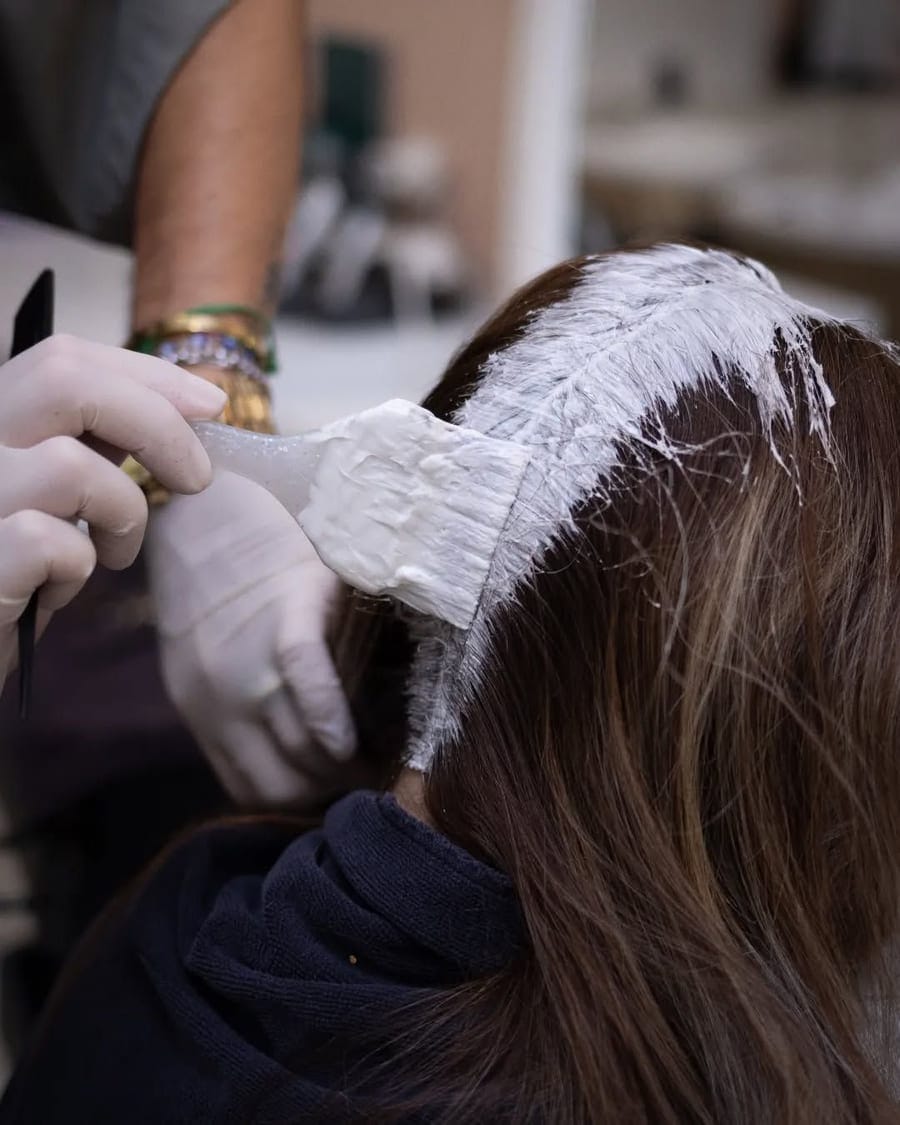 Color being applied at the root to blend regrowth into existing color